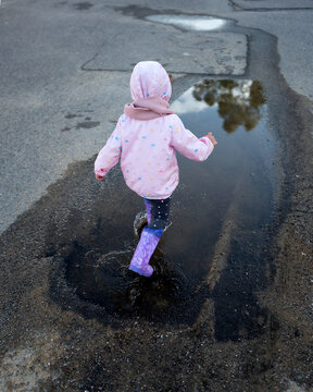 Toddler playing in a puddle on the street