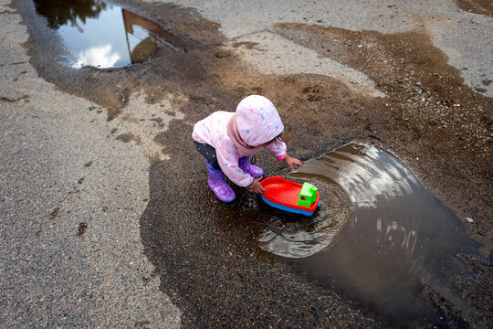 Toddler playing in a puddle on the street