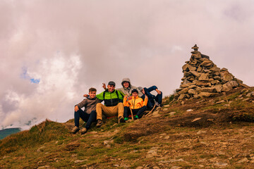 Obraz premium A group of tourists are sitting smiling on top of the mountains of the Montenegrin ridge, Mount Rebra is one of the peaks of the Carpathian mountains.