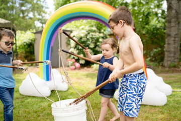 Siblings dipping huge bubble wands into bucket