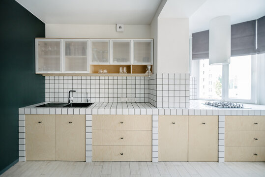 Kitchen in white tilles and a grey wall in a minimalist apartment