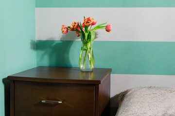 Vase with white and red tulips on table in bedroom. Interior element