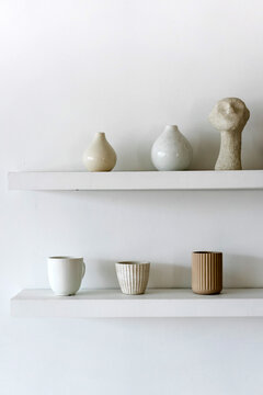 Set of ceramic pots and cups on shelf
