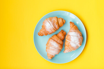 Cup of espresso coffee and croissant on yellow background, copy space