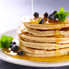 stack of pancake with pouring syrup