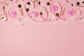 Top view photo of birthday composition with pink ribbon stars golden taper candles serpentine and confetti on isolated pastel pink background with copyspace