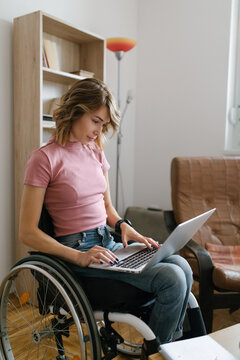 Young woman in a wheelchair working from home on her laptop