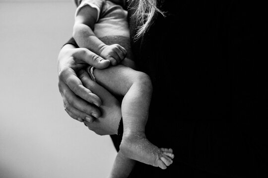 Faceless black and white image of mom holding baby