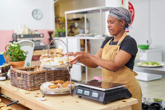 Deli owner arranging baked goods in a local store
