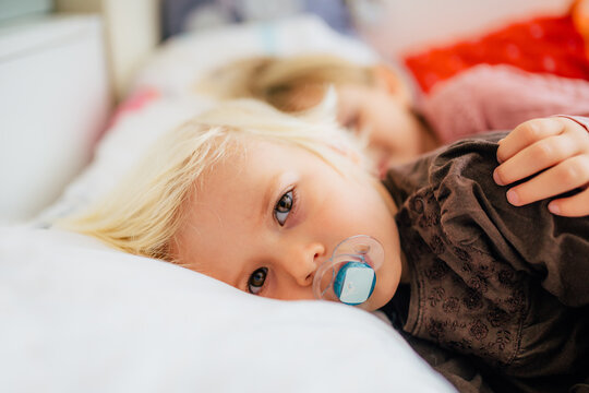Little kid with pacifier lying in bed