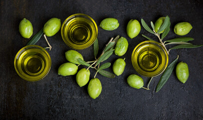 Olive oil and olive branch on black background