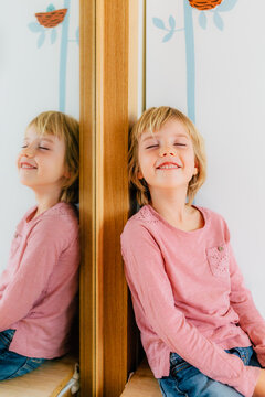 Smiling little girl standing near mirror