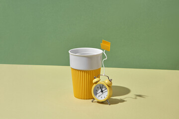 Alarm clock as a teabag near ceramic reusable cup.