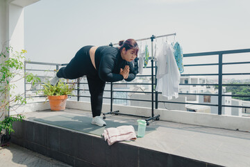 Health, fitness and sports concept. Plus size young asian woman doing exercise on mat in balcony, going to loose extra pounds at home, become strong and fit, training endurance.