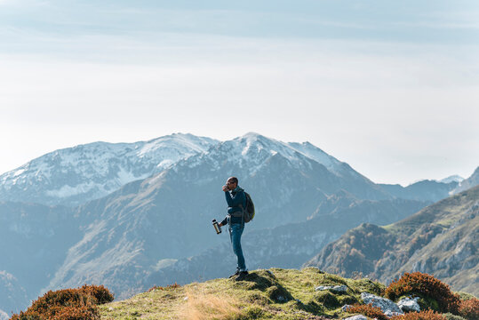 Hiker drinking tea from thermos at summit of mountain