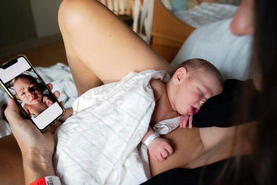 Mother of Newborn Baby Looks at Pictures on her Phone