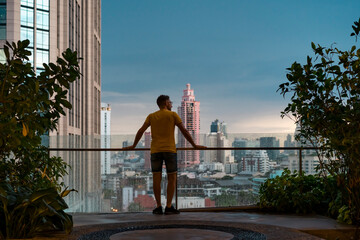 Traveller looking at the view of skyscrapers at sunset in Bangkok, Thailand.