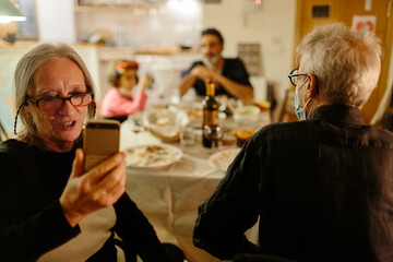 Woman video chatting with a family member at home at night during a family celebration