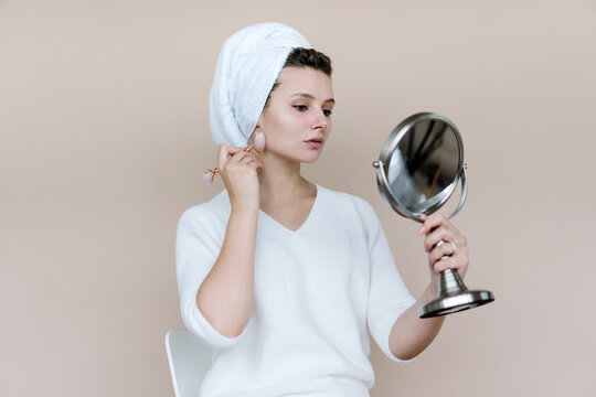 Young woman doing facial massage with quartz roller