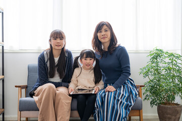 ソファに座る姉妹と母親