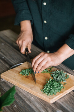 Anonymous Woman Cutting Fresh Mint Sage And Marjoram For Handmade Dolmadakia