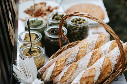 Outdoor table with french baguettes in a basket, olives and other spreads