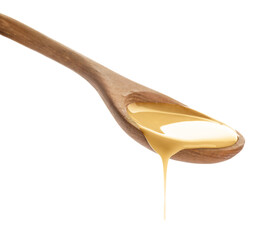 Wooden spoon of condensed milk on white background
