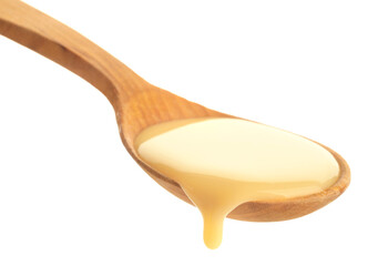 Wooden spoon of condensed milk on white background