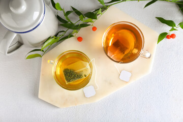 Cups of aromatic green and black tea on light background