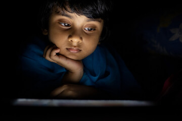 Little girl watching and browsing movie in a tablet inside room