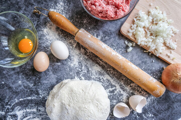 The ingredients for baking cakes with meat-tat. A dish of national Tatar and Bashkir cuisine. Ground beef, dough, eggs, onions. Gray background.