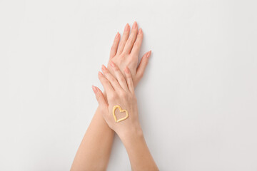 Heart made of cream on hand of young woman on white background