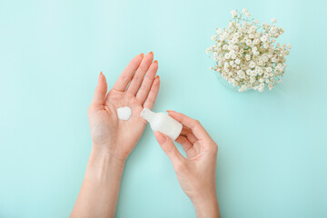 Young woman applying cosmetic product on color background