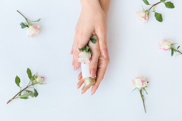 Obraz na płótnie Canvas Female hands with cosmetic product and beautiful flowers on light background