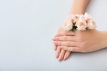 Female hands with beautiful flowers on color background