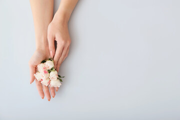 Female hands with beautiful flowers on color background