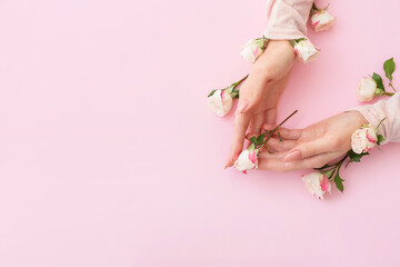 Female hands with beautiful flowers on color background