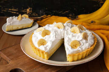 Plate with tasty banana pie on wooden background