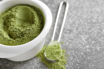 Bowl with henna and spoon on grunge background, closeup