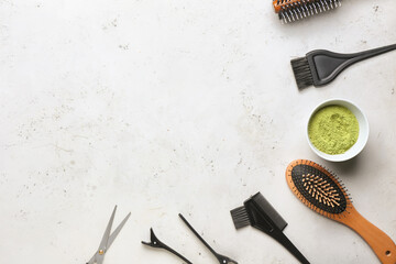 Bowl with henna and hairdresser's supplies on light background