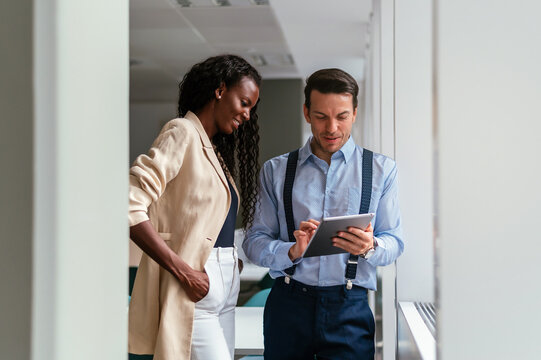 Multiethnic managers with tablet discussing work in office