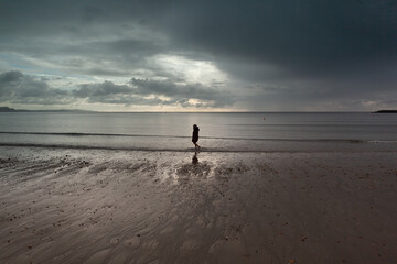 Child on a beach under a stormy sky