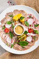 Cold Cut Meat Platter. Rustic style meat appetizers with dip and vegetables. Snack plate on grey table with sack napkin.