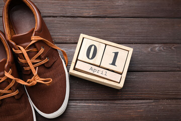 Shoes with tied laces and calendar with date of April Fools Day on wooden background