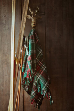 Old skis and poles against wall with green plaid blanket