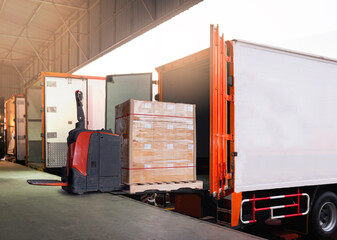 Electric Forklift Loading Shipment Boxes into Cargo Container. Cargo Trailer Truck Parked Loading...