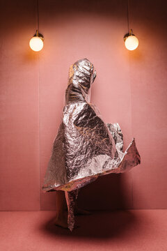 model wrapped with an aluminium blanket in a pink room