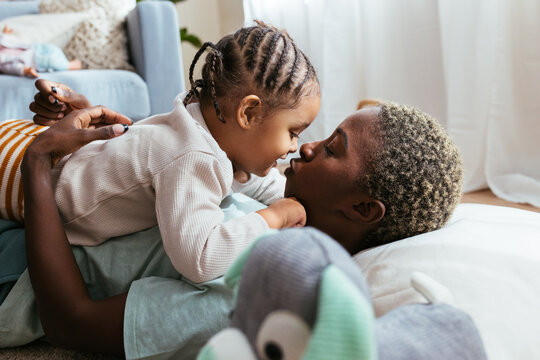 Black mother and daughter kissing at home