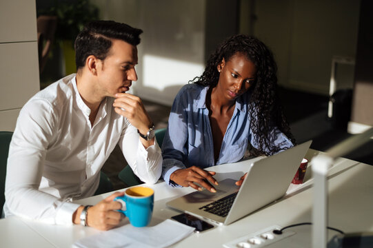 Focused multiracial coworkers analyzing data on laptop
