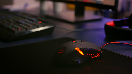 Fototapeta na wymiar Closeup of professional mouse with RGB lighting during online shooter video games tournament. Home studio of esport video game player using powerful gaming PC